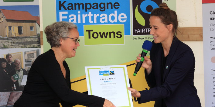 Foto: Lisa Herrman von Transfair überreicht der Beigeordneten die Auszeichnung © Stadtverwaltung Erfurt / J. Ludwig Zwei Frauen, die eine überreicht der anderen eine Urkunde.
