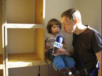 Mann und auf Schrank sitzendes Kind am Mikrofon