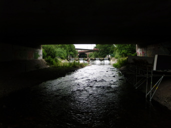Ein Fluß fließt unter verschiedenen Brücken. Düstere Situation.