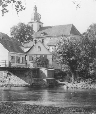 Schwarz-Weiß-Aufnahme einer Kirche, im Vordergrund Häuser.