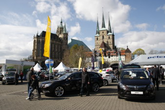 Verschiedene Automobile, präsentiert auf dem Domplatz, dazwischen verschiedene Fahnen. Im Hintergrund Dom und St. Severi.