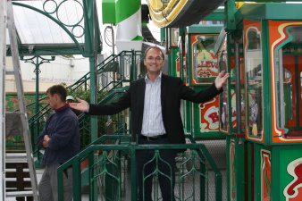 Ein Mann, voller Freude, steht am Eingang zu den Gondeln eines Riesenrades.