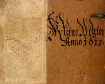 Ein Detail eines Buchumschlages, links ein Wappen, rechts eine alte Schrift.