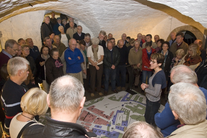Foto: Aktionstag "6. November 1813 – Der Tag der Erfurt veränderte" © Stadtverwaltung Erfurt / D. Urban Zahlreiche Personen in der Sonderausstellung des Stadtmuseums. Die Kuratorin, mit Brille, erklärt die Domplatz-Karte.