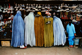 Fünf Frauen an einem Marktstand, an dem Turnschuhe verkauft werden.