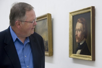 Ein Herr schaut auf ein Porträtgemälde. 