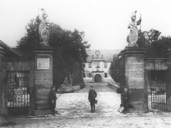 Drei Jungen mit Knickerbockern stehen am Steinportal des Schlosseinganges. 