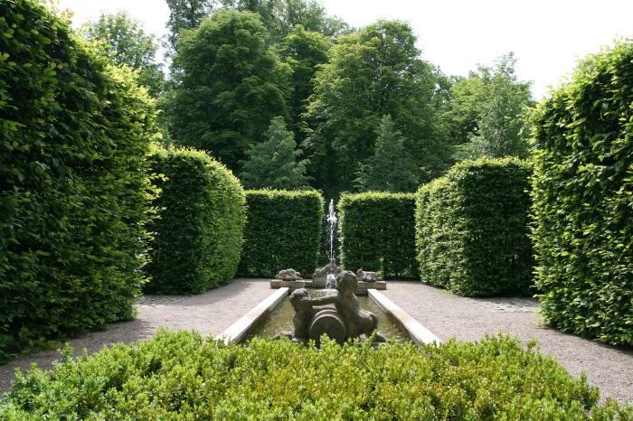 Lapidarium im Schlosspark Molsdorf Steinskulpturen mit kleiner Fontäne inmitten einer von Hecken umsäumten Parkanlage.
