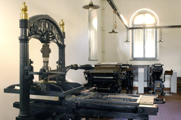Historische Kniehebelpresse aus dem Jahre 1865 Große, gusseiserne Maschine mit einem Hebel. Im Hintergrund weitere Maschinen.