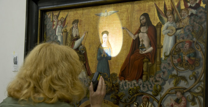 Mitarbeiterin hält Lichtquelle auf die dargestellte Maria und den über ihr befindlichen heiligen Geist.