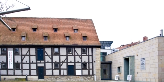 Fachwerkhaus mit rotem Dach, rechts ein moderner Anbau.