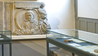 Steinepitaph und Ausstellungsvitrinen mit ausgelegten Urkunden.