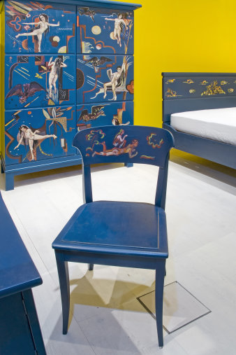 Blaue Schlafzimmermöbel mit Bemalung - im Vordergrund steht ein Stuhl, dahinter sind Bett und Kleiderschrank zu sehen