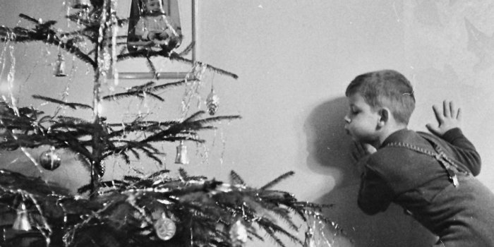 Schwarz-weiß Foto eines Kindes, das die Kerzen einen Weihnachtsbaumes auspustet