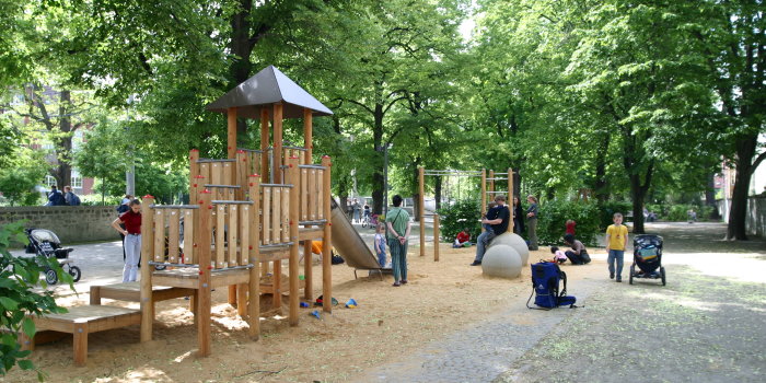 Kinder spielen auf Spielgeräten inmitten eines grünen Parks.