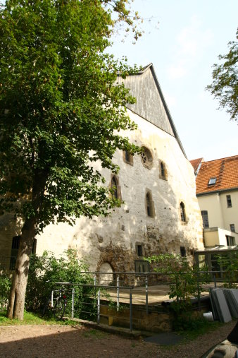 Giebelseite eines sehr alten Gebäudes. Links ein Baum.