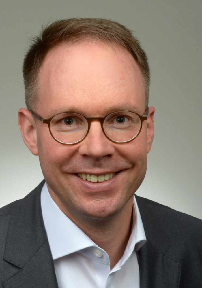 PD Dr. Notker Baumann Ein Herr mit runder Brille schaut freundlich auf den Betrachter.