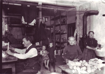 Foto: Glasbläserfamilie bei der Heimarbeit, Lauscha, um 1910 © Museum für Thüringer Volkskunde Erfurt, Inv. Nr. 49 Vater, Mutter und drei Kinder in einer Werkstatt bei der Arbeit.