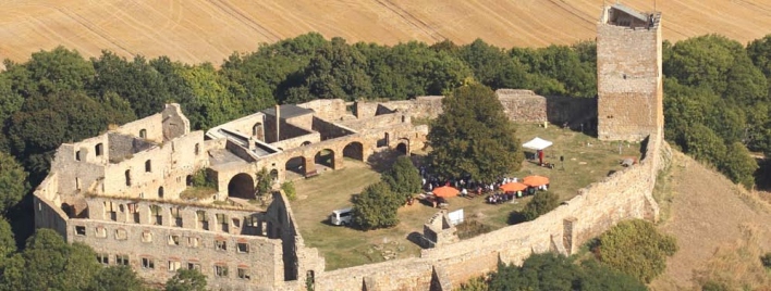 Foto: Burg Gleichen bei Wandersleben © Reinhard Lemitz Eine Ruinenanlage, umrahmt von Wald. Im Hintergrund ein Feld.