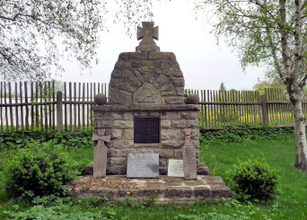 Denkmal aus Naturstein, an das Gedenkplatten gelehnt sind