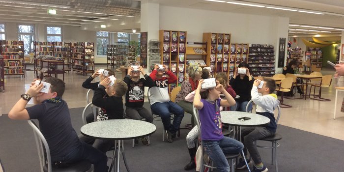 Kinder mit Virtual-Reality-Brillen in einer Bibliothek