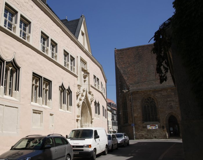 Collegium Maius – die Alte Universität zu Erfurt Ein mittelalterlicher Bau links, zart rosé gehalten, im Hintergrund blauer Himmel