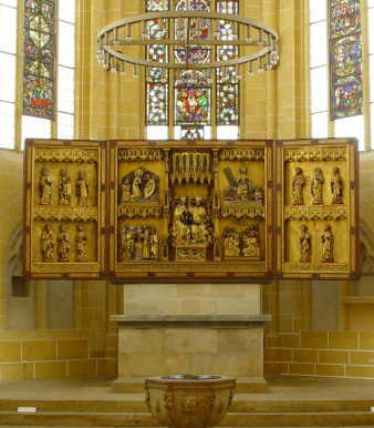 Ein Altar in einem Kirchenraum, davor ein Taufbecken.