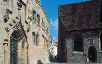 Links im Bild die wiederaufgebaute Universität, rechts ein Teil der Universitätskirche.