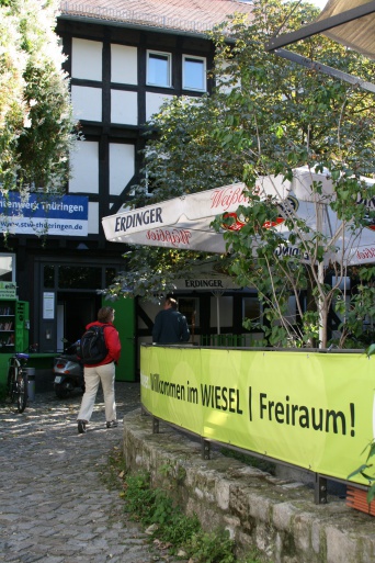 Ein grünbewachsener historischer Innenhof, rechts ein grünes Banner.