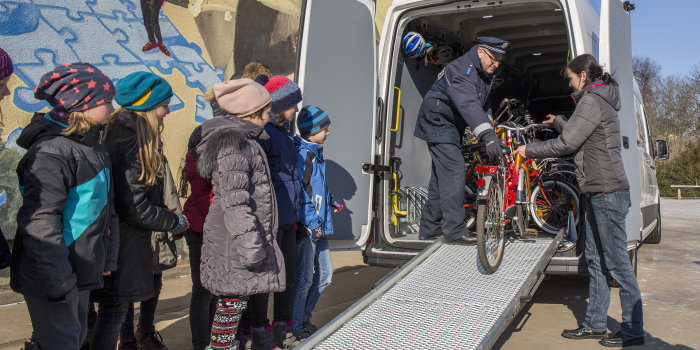 Schüler und Polizist an einem Transporter mit Fahrrädern