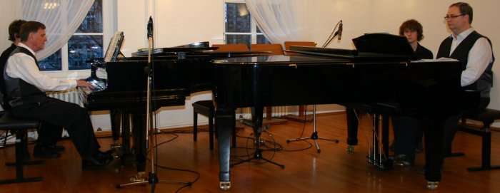 Klavierduo Kohlert/Nedeß An zwei einander gegenüberstehenden Flügeln sitzen zwei Pianisten und ihre Assistenten.