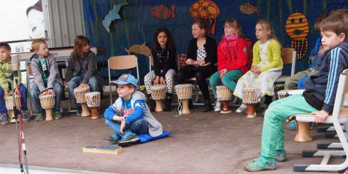 Die Kinder der Percussiongruppe „Trommelwirbel“ mit ihren Instrumenten bei einem Auftritt im Hof der Musikschule