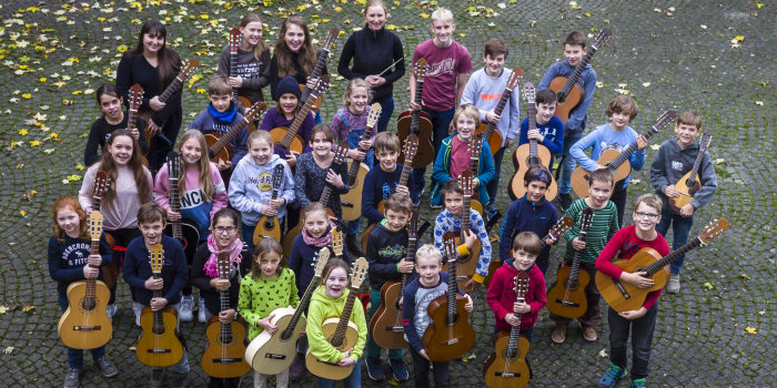 Kinder mit Zupfinstrumenten im Hof der Musikschule