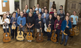 Die Mitglieder des Kinderzupforchesters mit ihren Instrumenten und ihrer Leiterin, Frau Laier, im Saal der Musikschule