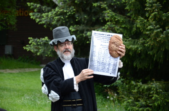 Foto: Mathematischer Wettstreit an der Volkshochschule Erfurt © Michal Smatana Ein Mann, verkleidet als Adam Ries, hält ein Blatt mit mathematischen Rechnungen und ein Stück Brot in die Höhe.