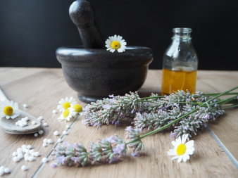 Foto: Homöopathie © Stadtverwaltung Erfurt Kamillen- und Lavendelblüten vor einer Mörserschale.