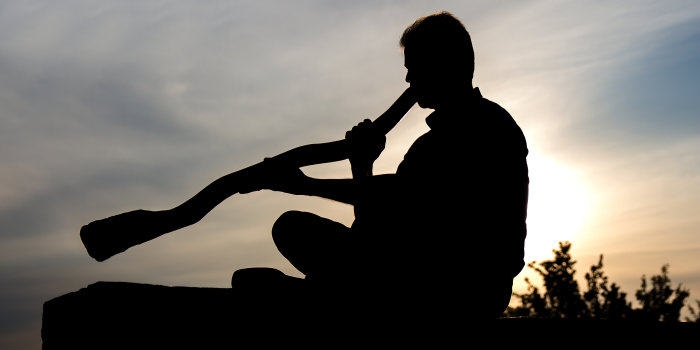 Foto: Didgeridoo © Stadtverwaltung Erfurt/Grit Kästner Silhouette: Gegen den Sonnenuntergang sitzender Mann, ein Didgeridoo spielend