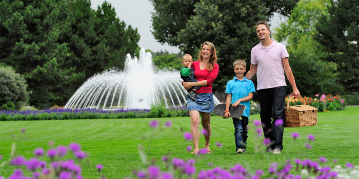 Familie läuft über Rasen vor eiem Springbrunnen