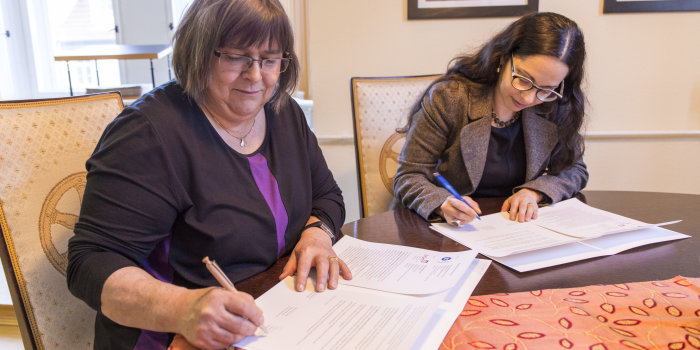 Zwei Damen bei der Unterzeichnung eines Vertrages.