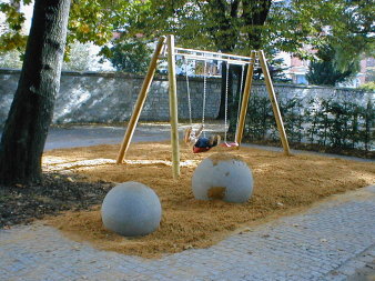 Sandfläche mit Schaukel und zwei Betonkugeln