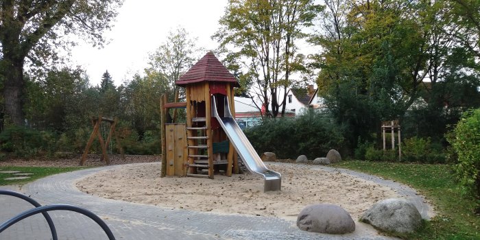 große Sandfläche mit Kletterturm aus Holz und Rutsche