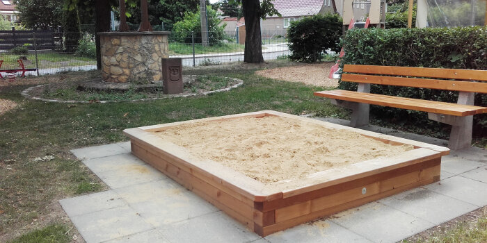 ein Sandkasten, daneben eine Sitzbank