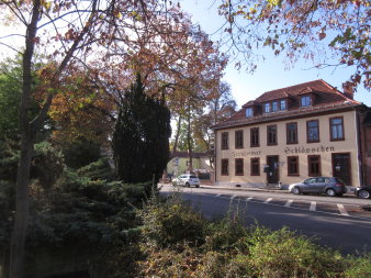 An einer Hauptstraße stehendes und als Gaststätte genutztes zweigeschossiges Gebäude. Auf der hellen Fassade, oberhalb des Erdgeschosses prangt der Schriftzug "Hochheimer Schlösschen"
