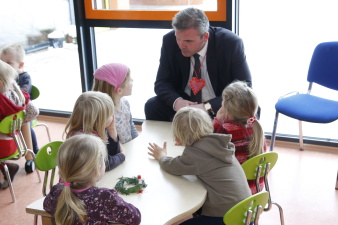 Der Oberbürgermeister sitzt mit mehreren Kindern an einem Tisch und unterhält sich mit ihnen.