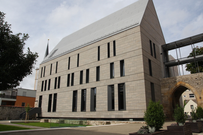 Außenansicht des Bibliotheksgebäudes mit Spitzdach und moderner Fassade aus Glas und Beton