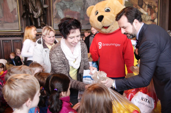 Eine Gruppe Kinder erhält einen Sack mit Plastikenten von einem der Sponsoren