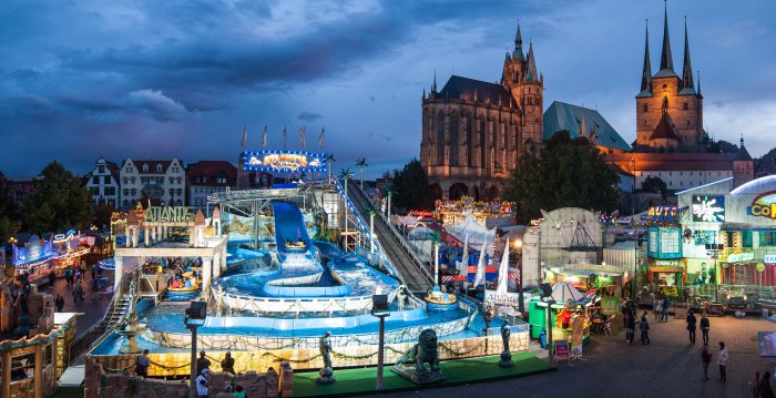 Foto: Die Atlantis-Rafting-Bahn lockt auf's Erfurter Oktoberfest. © Matthias F. Schmidt große Wasserrutsche im Abendlicht vor beleuchteter Silhouette von Dom und Severikirche