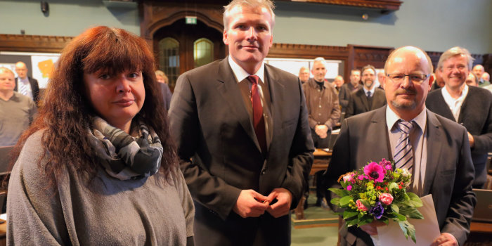 Der Erfurter Oberbürgermeister ehrt zwei Stadtratsmitglieder für ihre langjährige Arbeit und überreicht eine Urkunde und Blumen.