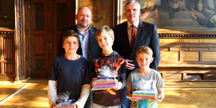 Drei Schüler erhalten vom Oberbbürgermeister und vom Leiter der Volkshochschule Urkunden.