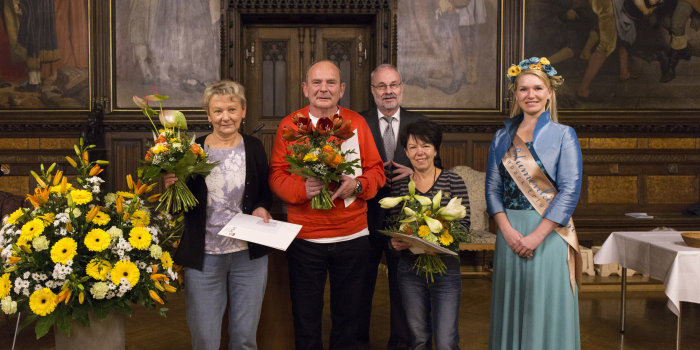 5 Blumenfreunde im historischen Festsaal der Stadt. Links ein prächtiges Blumengesteck.